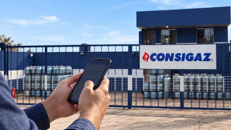 Consulta pelo celular diante do depósito com placa da Consigaz